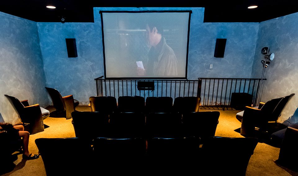 Room with multiple seats and a large screen, resembling a mini theater.