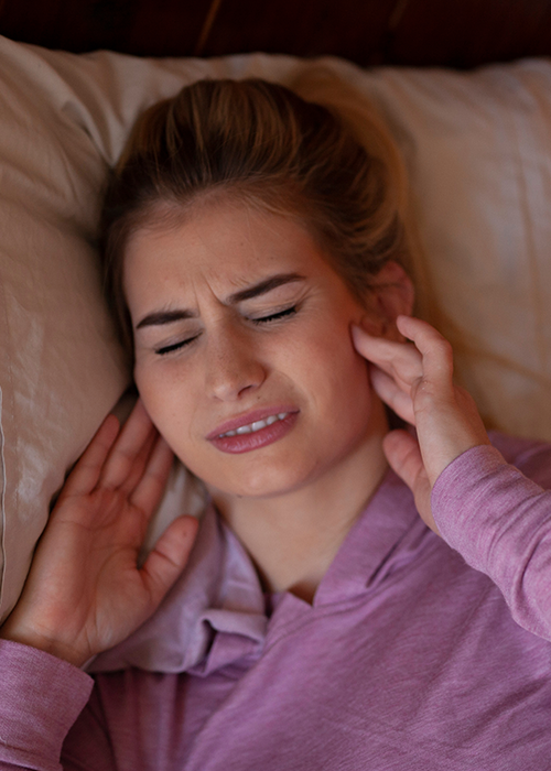 A woman showing discomfort from jaw pain.