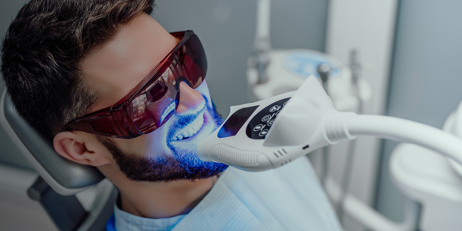 A man receiving a dental cleaning with ultraviolet light.