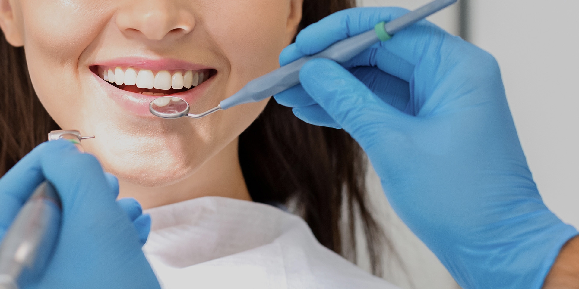A woman smiling with a dental mirror near the teeth.